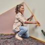 Frau klebt mit Bosch Laser-Wasserwaage UniversalWallLevel eine Wand ab.