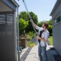 Mann reinigt Dachrinne mit Gardena combisystem Dachrinnenreiniger und Teleskopstiel.