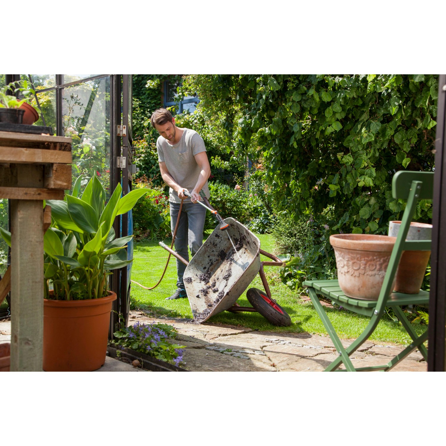 Mann reinigt Schubkarre mit Gardena Comfort Gießstab 90 cm im Garten.