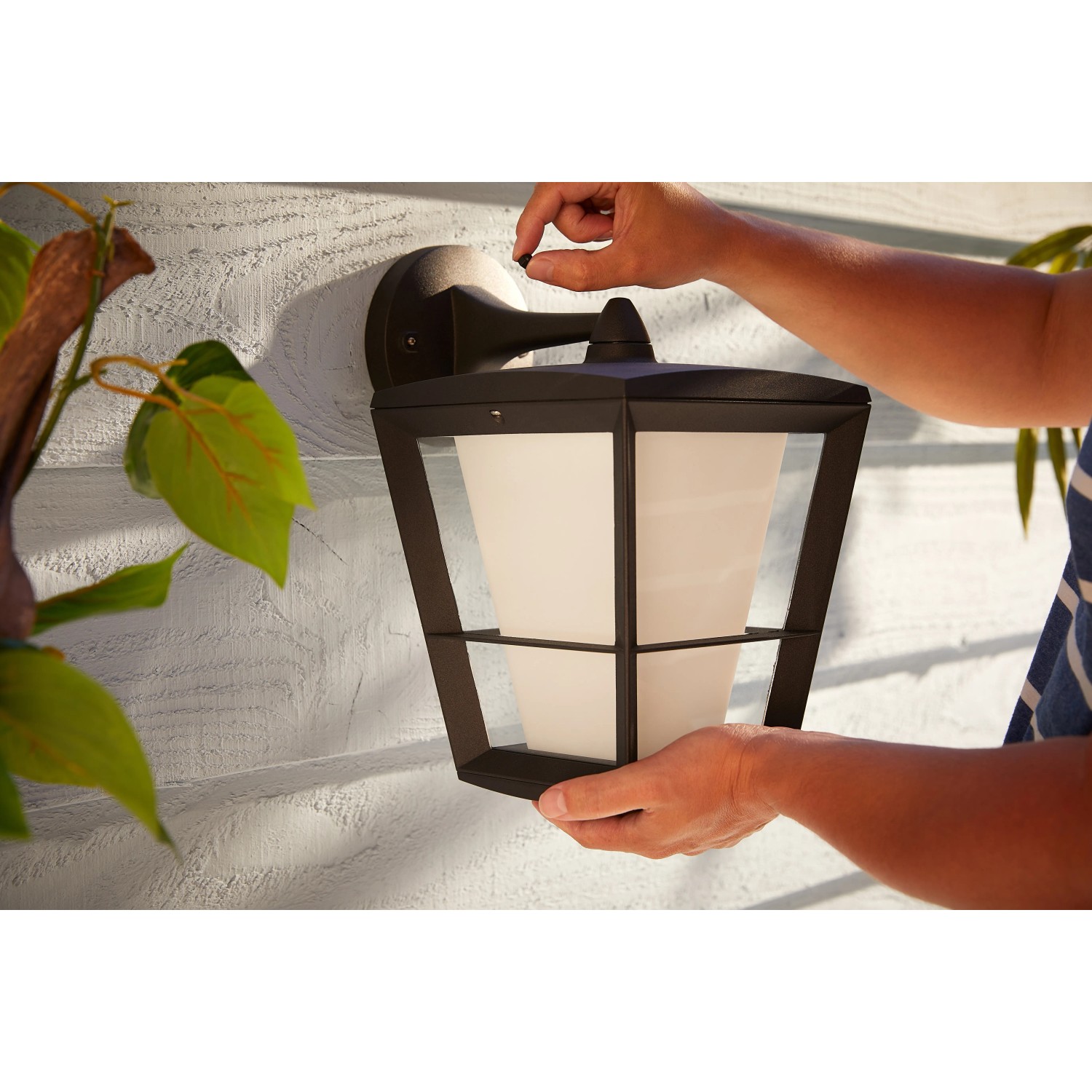 Hängende Philips Hue Econic LED-Laternenleuchte in Schwarz wird an einer Wand montiert.
