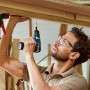 Mann schraubt mit Bosch Professional Akku-Bohrschrauber GSR 12V-35 Schraube in Holz.