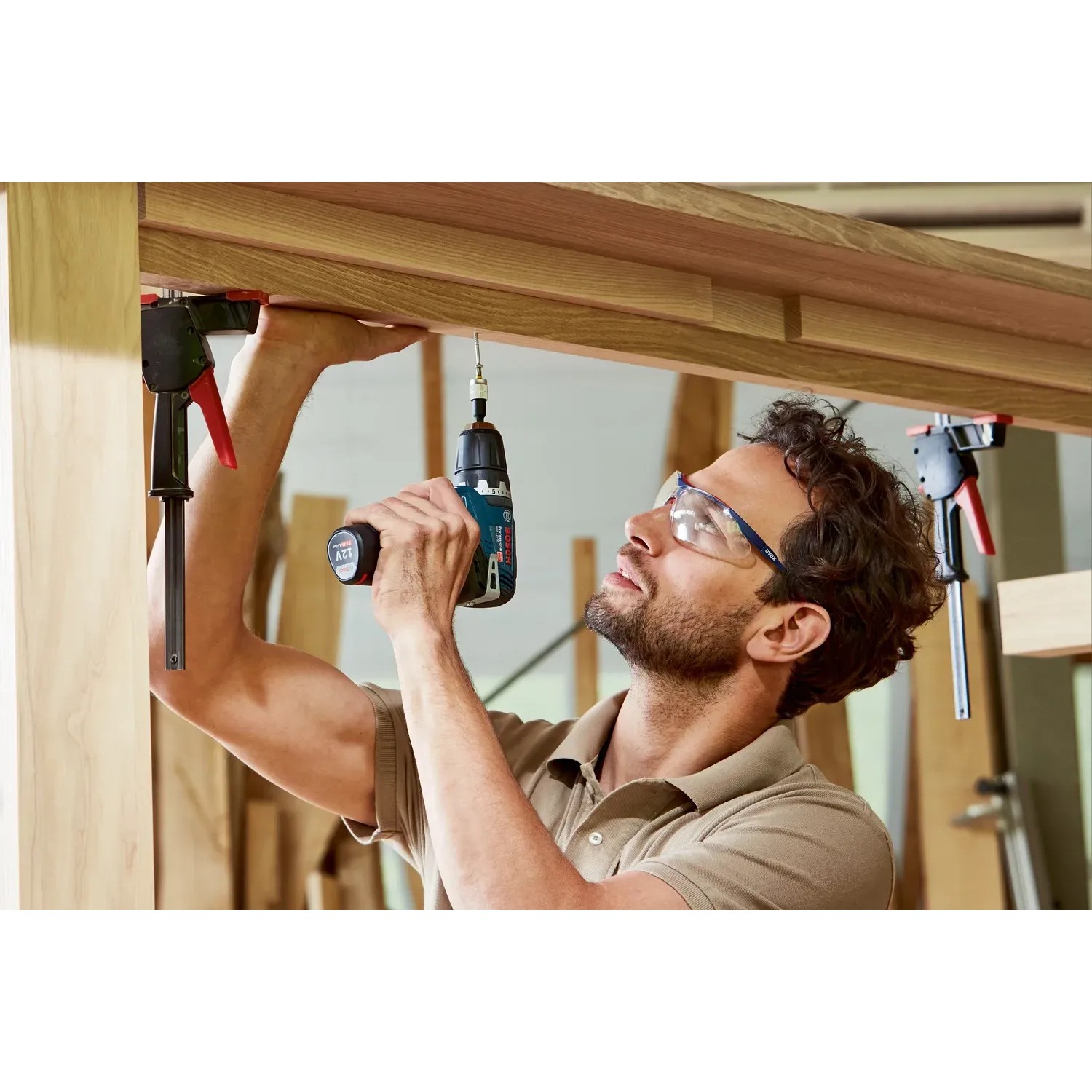 Mann schraubt mit Bosch Professional Akku-Bohrschrauber GSR 12V-35 Schraube in Holz.