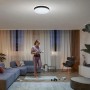 Schwarze Philips Hue Enrave XL Deckenleuchte mit warmweißem Licht in modernem Wohnzimmer.