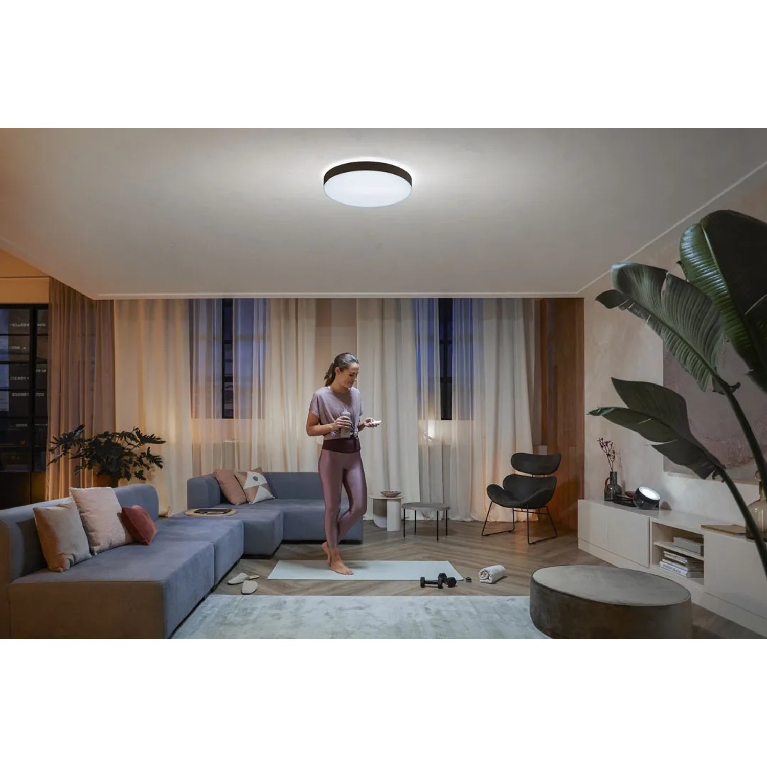 Schwarze Philips Hue Enrave XL Deckenleuchte mit warmweißem Licht in modernem Wohnzimmer.