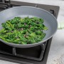 Graue Fackelmann Antihaftpfanne Ecolution (Ø 20 cm) mit Spinat auf einem Herd.