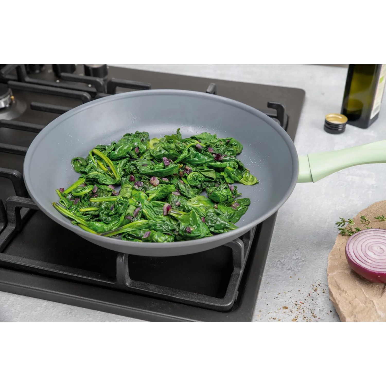 Graue Fackelmann Antihaftpfanne Ecolution (Ø 20 cm) mit Spinat auf einem Herd.