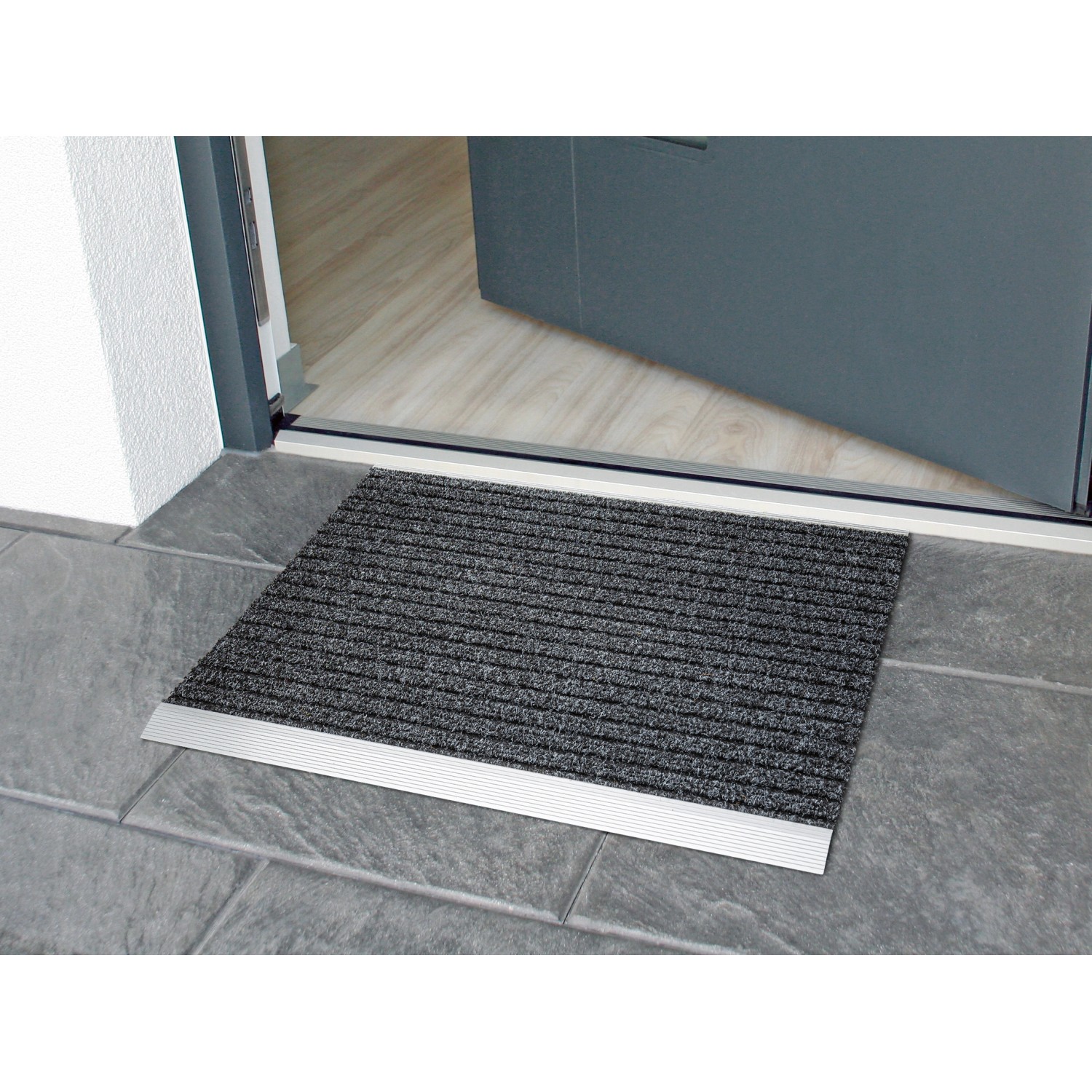 Anthrazit Fußmatte Lincon Alu-Rips, 37x58 cm, vor einer geöffneten Tür auf Fliesenboden.