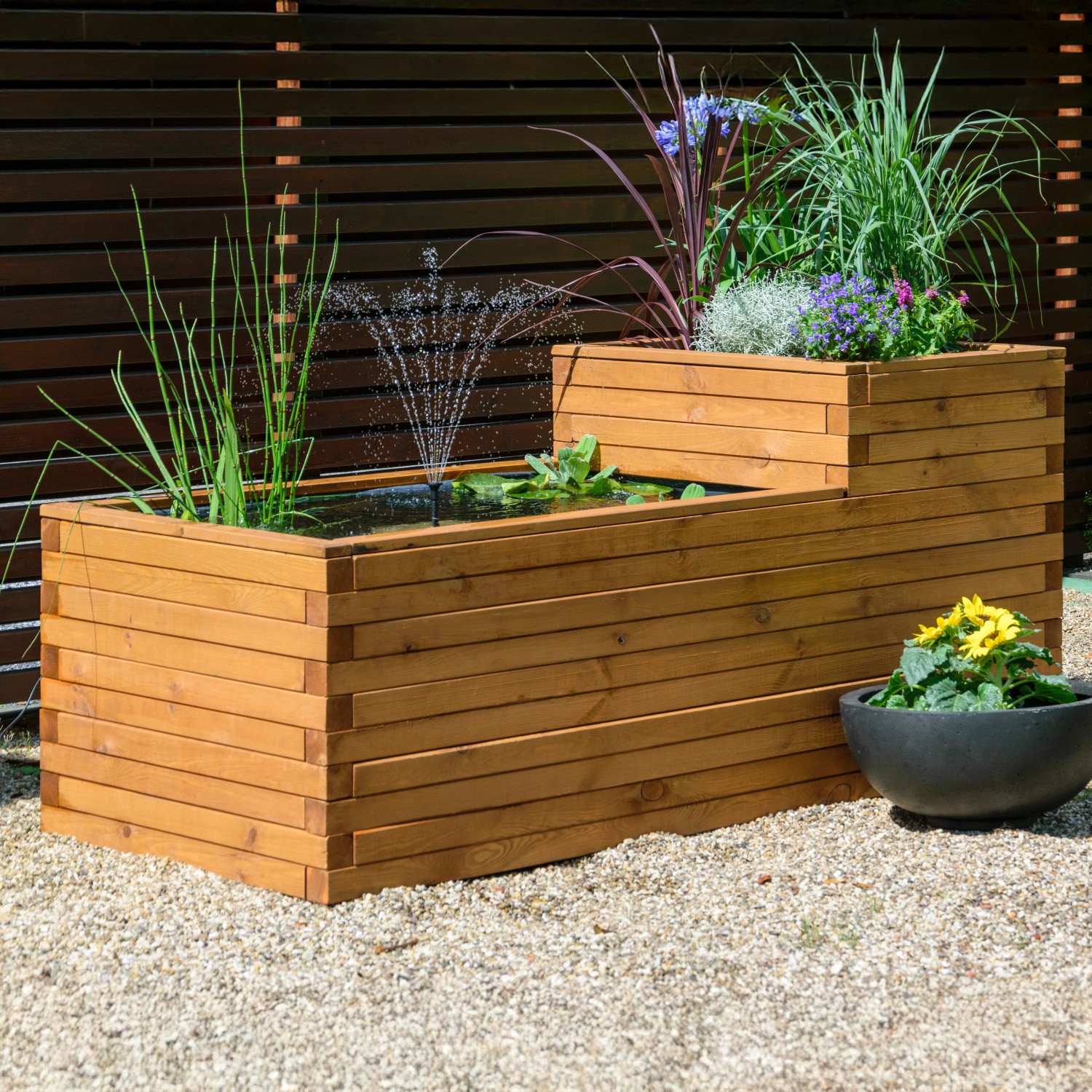 Braun lasierter Dobar Gartenteich Superb aus Kiefernholz mit Pflanzen und kleinem Springbrunnen.