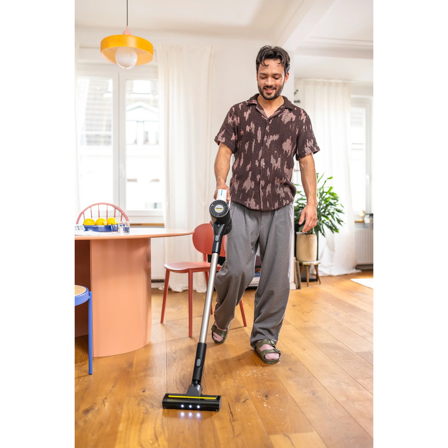 Mann saugt mit dem weißen Kärcher Akku-Staubsauger VCS 3 Nano Complete Holzboden.