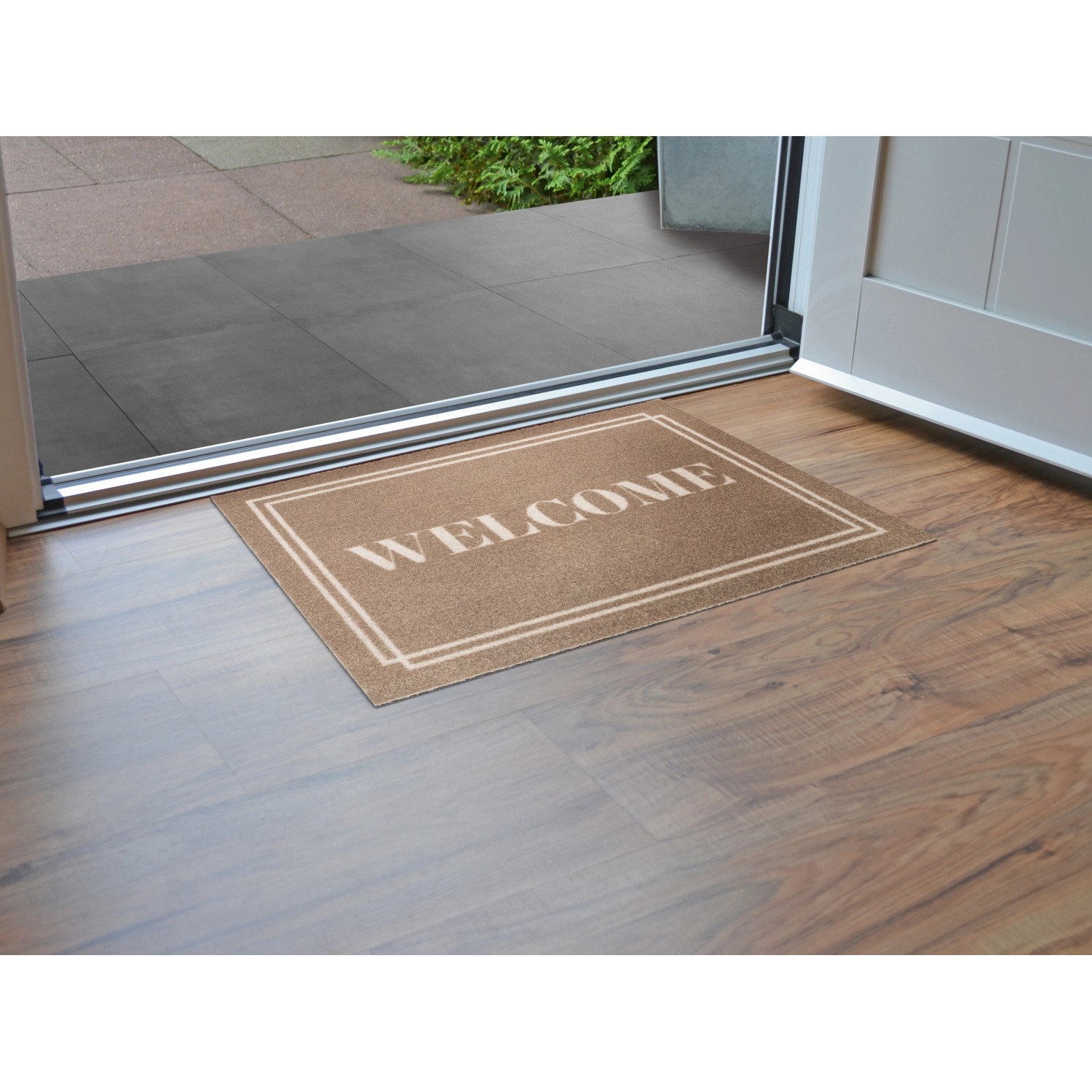 Fußmatte Welcome, 40x60 cm, braun, vor einer Tür auf Holzboden.
