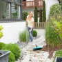 Frau kehrt Laub mit Gardena combisystem-Besen und Holzstiel 130 cm im Garten.