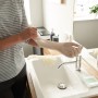 Frau zieht Vileda Einmalhandschuh Natural Latex Extra Long an Spüle an. Haushaltshandschuhe schützen.