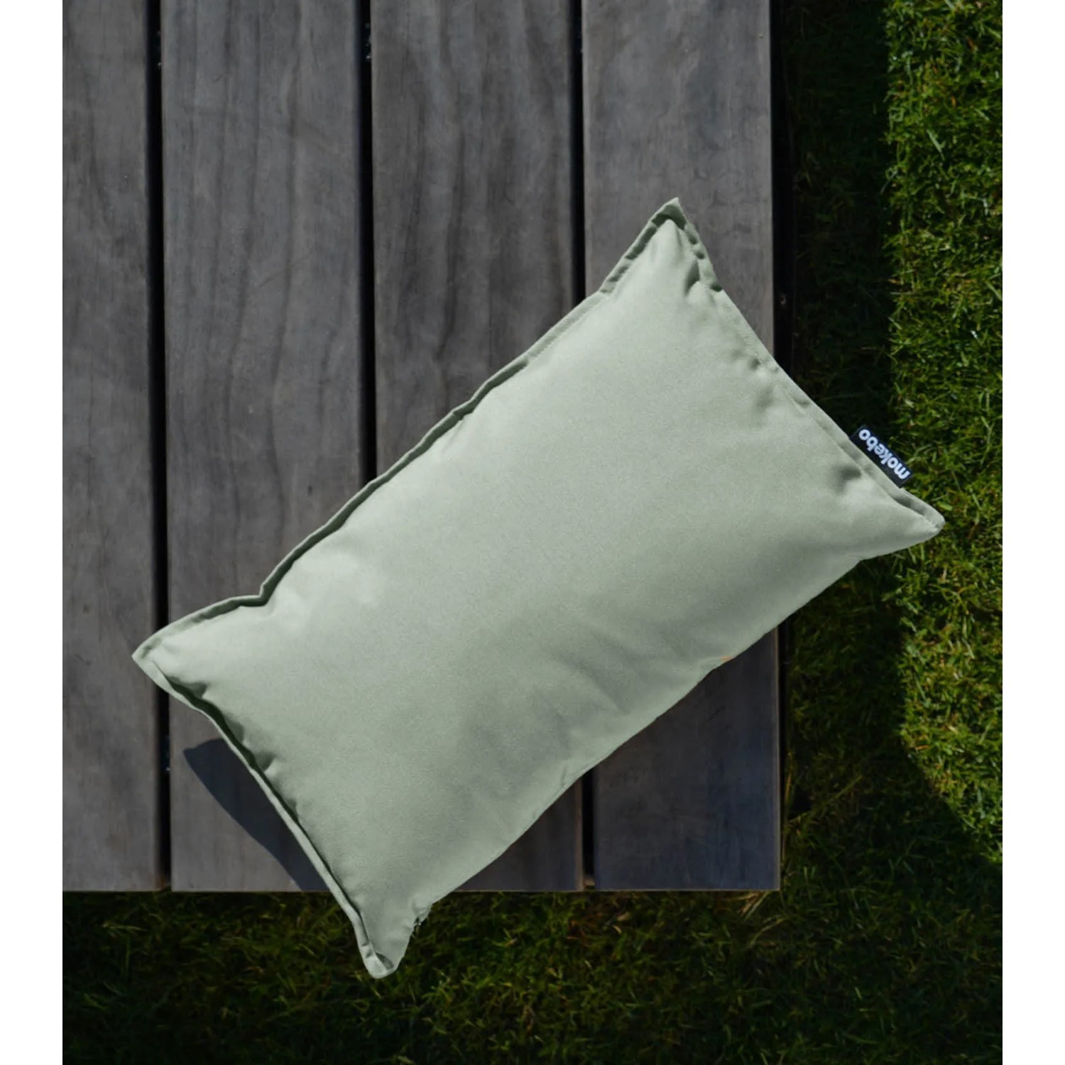 Lindgrünes mokebo Outdoor Kissen 'Das Ruhepolster' 50x30 cm auf Gartentisch.