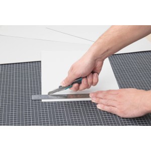 Wolfcraft Sicherheitsmesser schneidet Papier mit Lineal auf Schneidematte.