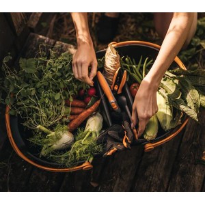 Fiskars Erntekorb Plus, gefüllt mit Gemüse und Werkzeug, in Schwarz-Orange.