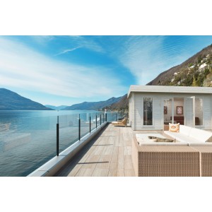 Hellgrau-anthrazitfarbenes Palmako Gartenhaus Bret (530x390cm) mit Terrasse und Seeblick.