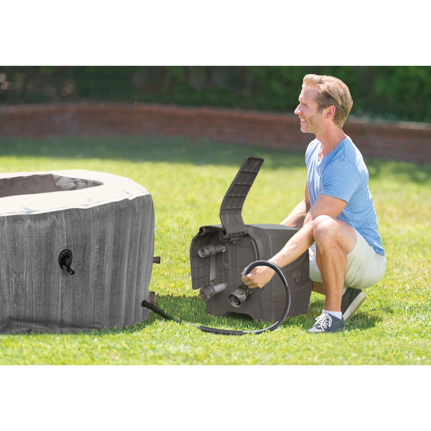 Intex PureSpa Greywood Deluxe: Aufblasbarer Whirlpool mit Mann bei der Installation im Garten.