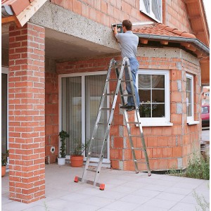 Krause Trimatic Gelenk-Doppel-Leiter im Einsatz: Mann arbeitet auf der Leiter an einem Haus.