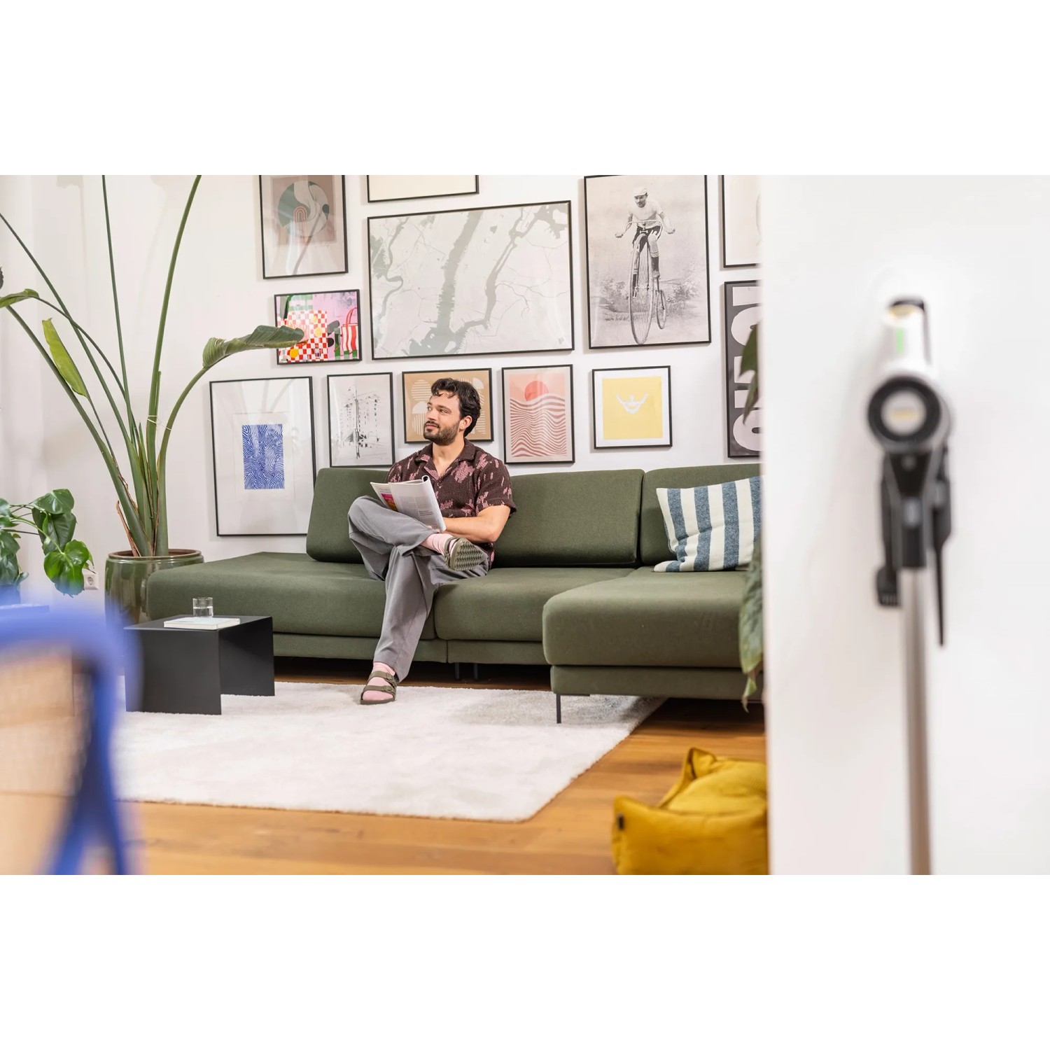Weißer Kärcher Akku-Staubsauger VCS 3 Nano Complete in Wohnraum-Szene mit Mann auf Sofa.