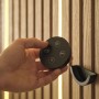Hand hält schwarze Fernbedienung für dimmbaren OSRAM LED Streifen, warmweiß leuchtend in Akustikpaneele.