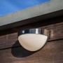 Lutec Solar-Außenwandleuchte Bubble aus Edelstahl an Holzwand, halbkugelförmig.