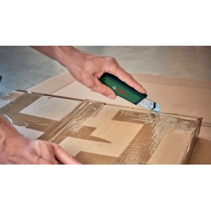 Bosch Cuttermesser im Einsatz: Hand schneidet Karton mit dem grünen Messer. Präzises Schneidwerkzeug.