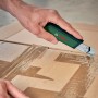 Bosch Cuttermesser im Einsatz: Hand schneidet Karton mit dem grünen Messer. Präzises Schneidwerkzeug.