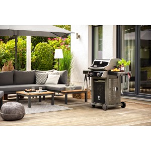 Gartenlounge mit grauer Eckcouch, Tisch und Grill auf einer Holzterrasse.