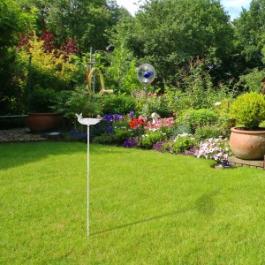 Weiße Gusseisen Vogeltränke mit Kolibri auf Erdspieß im grünen Garten. Blatt-Design Wasserschale für Wildvögel.