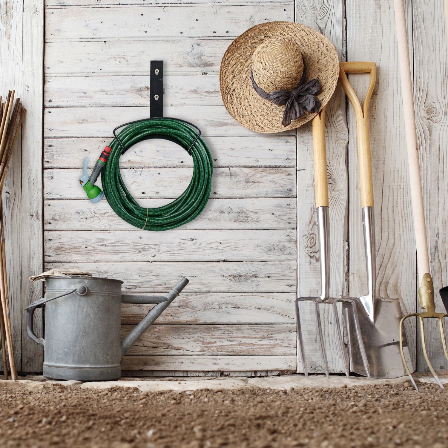 Schwarzer Stahl Schlauchhalter an Holzwand mit grünem Gartenschlauch. Platzsparende Aufhängung für Garten & Garage.