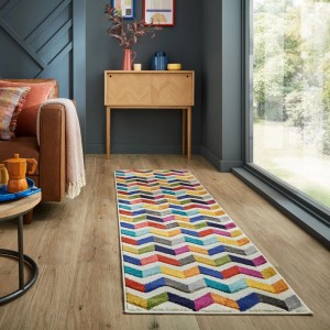 Langer, mehrfarbiger Flair Rugs Kinderteppich Bolero mit lebhaftem Zickzack-Muster auf Holzfußboden im Wohnzimmer.