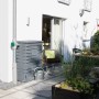 Arves Regentonne Maurano 300 l in Schwarz Granit Optik neben einem Fallrohr an einer Hauswand.