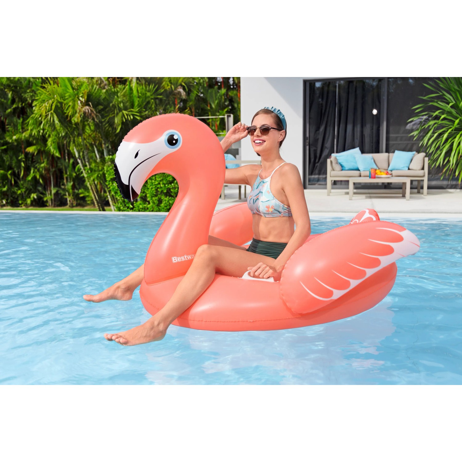 Frau auf großem, pinken Bestway Schwimmtier Flamenco im Pool.