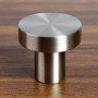 Runder SOTECH Möbelknopf EK03 aus gebürstetem Edelstahl, Ø30 mm, auf Holzoberfläche.