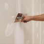 Anwendung von Knauf Uniflott Finish Feinspachtel auf Gipskartonplatte mit Spachtel.