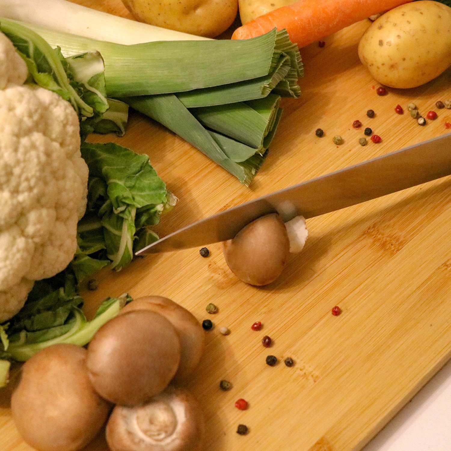 XL Schneidebrett aus Bambus mit Gemüse und Pilzen beim Schneiden.