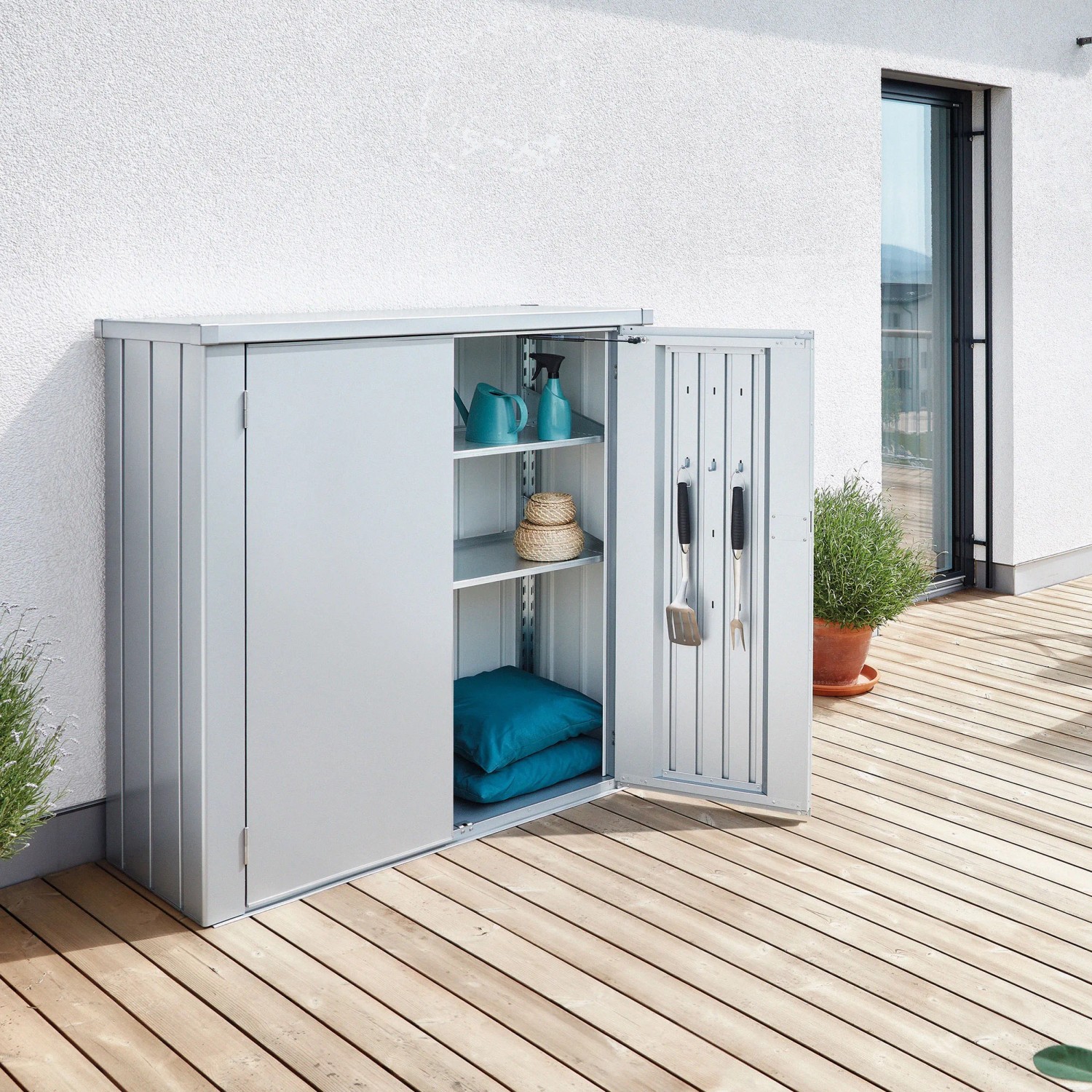 Silberner Biohort Terrassenschrank Romeo Gr. M mit geöffneter Tür auf einer Terrasse. Gartenschrank mit Regalen.