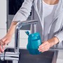 Frau befüllt Tank des Leifheit Akku-Saugwischers mit Wasser am Wasserhahn.