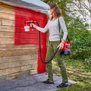 Frau lackiert Holz mit Einhell Akku Airbrush TE-SY 18/90 Li Solo Farbsprühgerät rot.