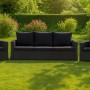 Anthrazitfarbenes 3-Sitzer Gartensofa mit Kissen und zwei Sesseln aus Polyrattan im Garten.
