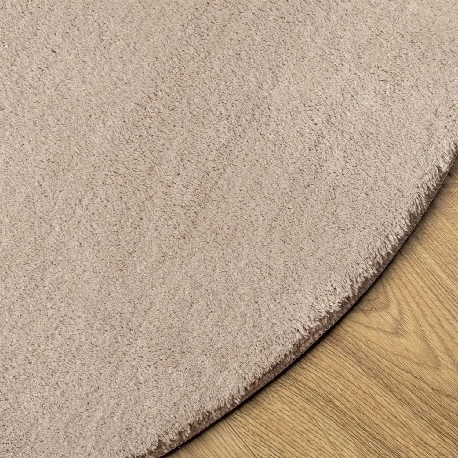 Sandfarbener runder Kurzflor-Teppich HUARTE (Ø 80 cm) auf Holzfußboden. Weich, flauschig und waschbar.