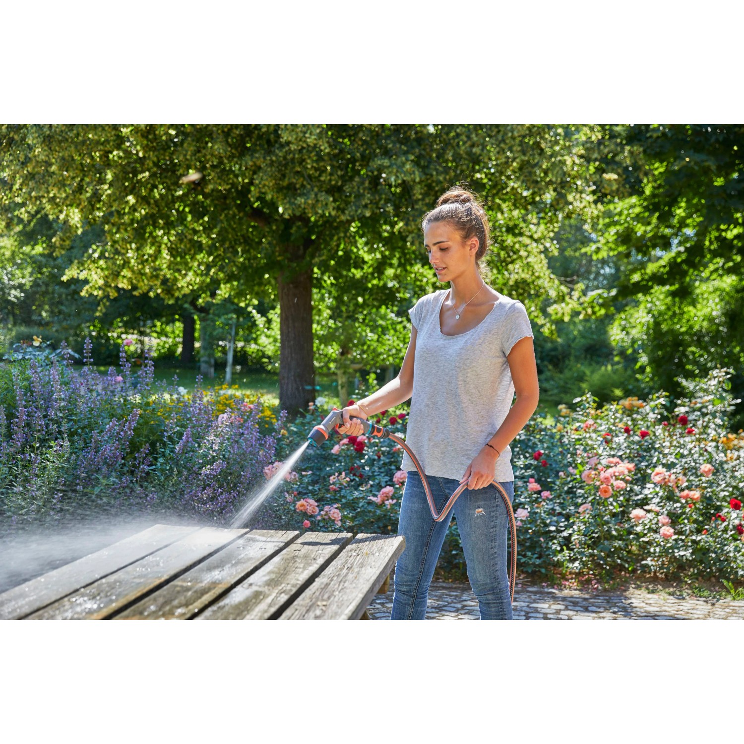 Frau reinigt Gartentisch mit Gardena Comfort Reinigungsspritze ecoPulse™.