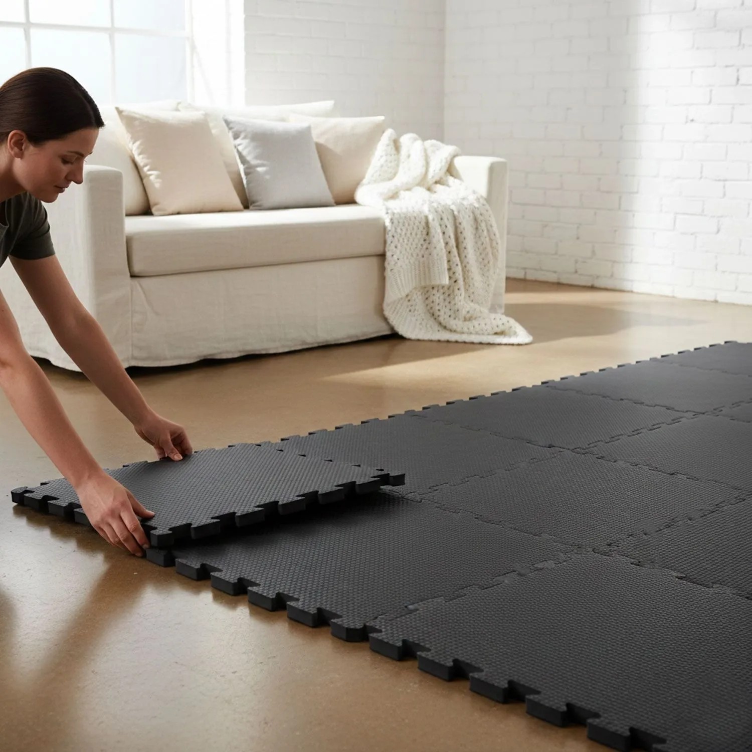 Person verlegt schwarze eyepower Bodenschutzmatten (30x30 cm) mit Puzzle-Verzahnung auf Holzboden für Home Gym.