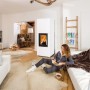 Weißer Haas+Sohn Kaminofen Dachstein mit Wärmespeicherbeton im Wohnraum mit brennendem Feuer.