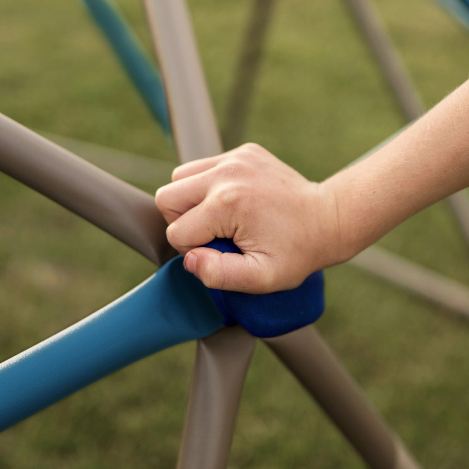 Detailaufnahme: Kinderhand greift nach Sprosse des Lifetime Klettergerüst Geodome.