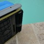 Akku-Poolroboter Orca 300 CL, Detailansicht der Bürsten und des Antriebs am Beckenrand.