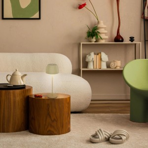 Brilo Akku-Tischleuchte Riffle lindgrün mit geriffeltem Schirm auf Holztisch im Wohnzimmer. Dimmbare Design-Tischlampe.