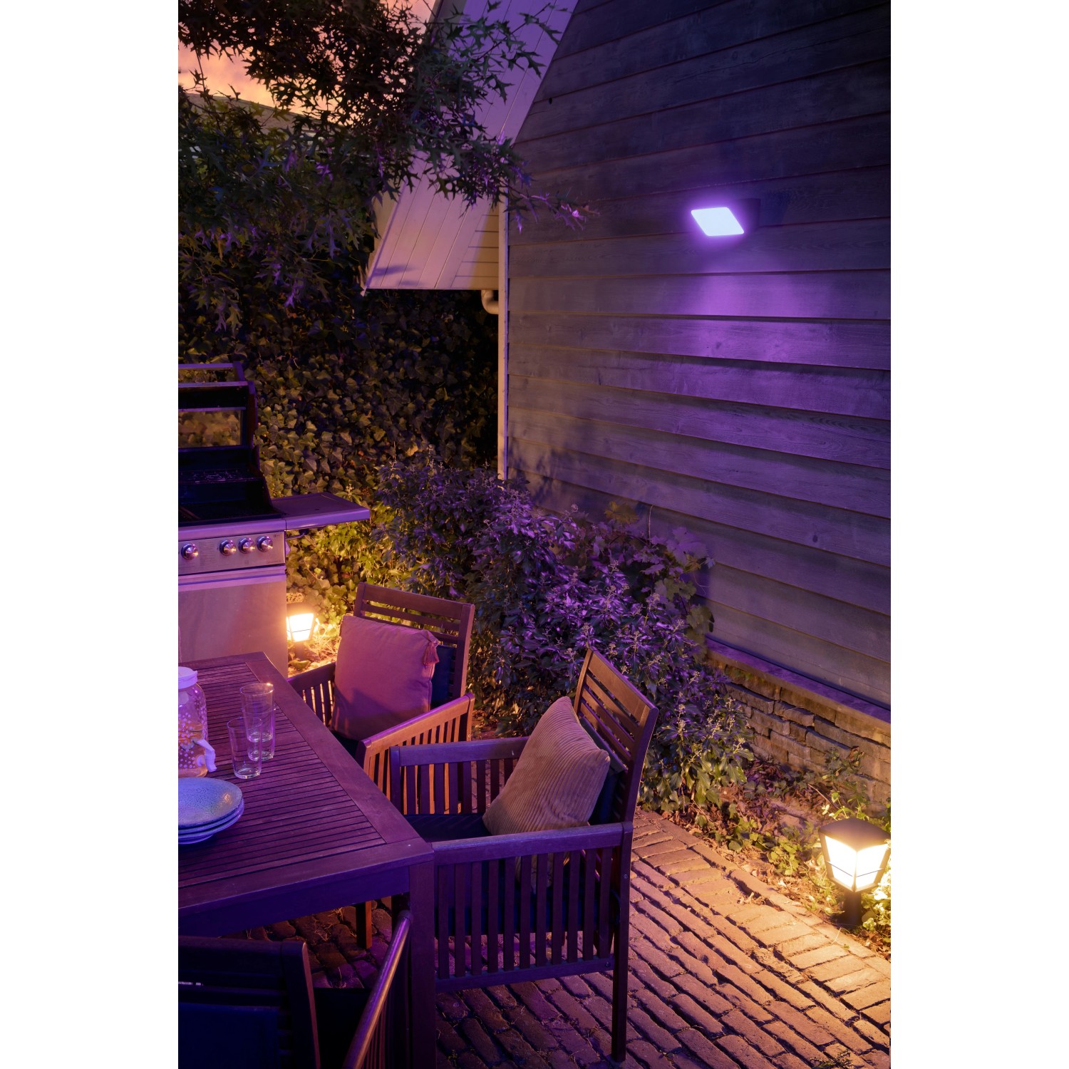 Philips Hue Econic LED-Sockelleuchte im Garten mit farbigem Licht. Außenleuchte aus Aluminium, wetterfest.