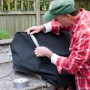 Mann repariert Abdeckung mit Duck Tape® Gewebe-Klebeband in Silber. Rolle Klebeband sichtbar.