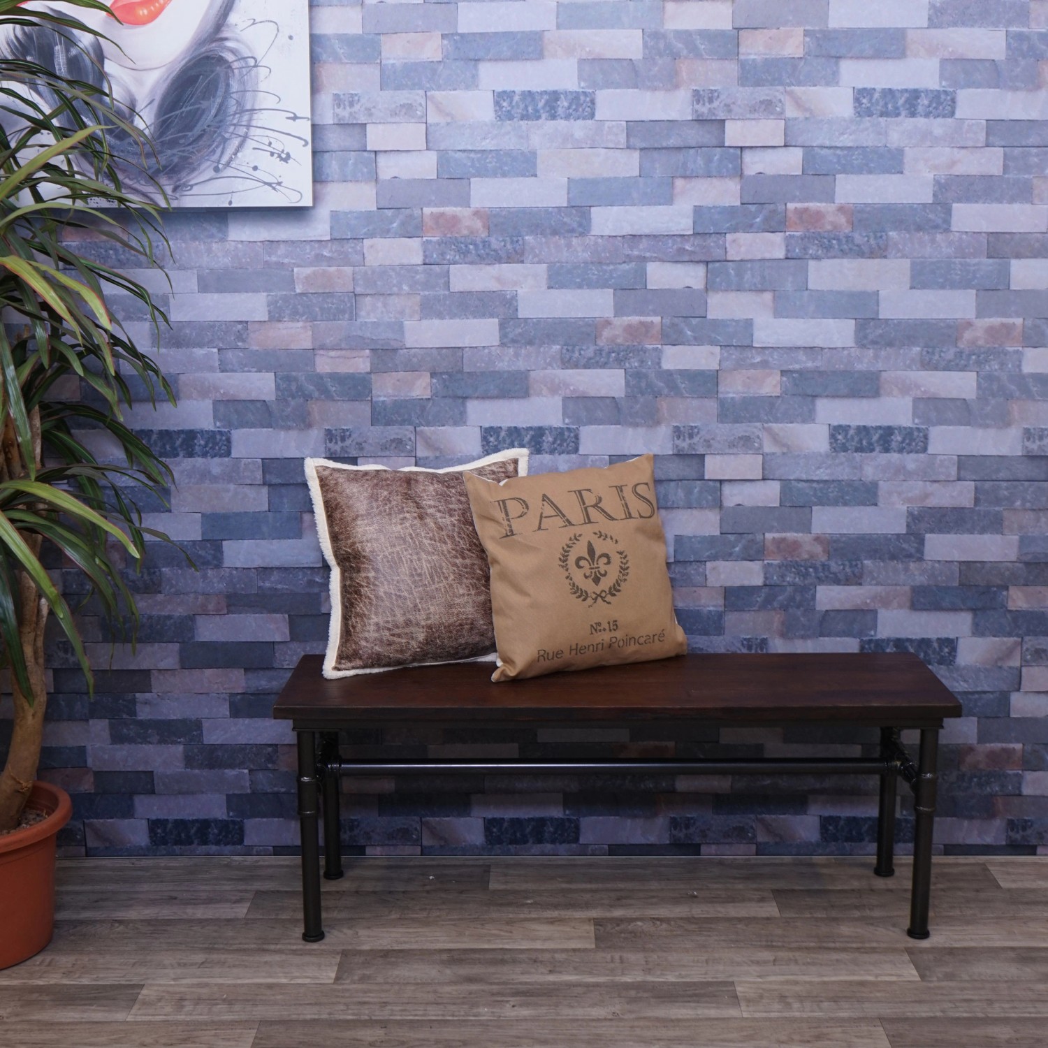 MCW Sitzbank H10b im Industrie-Stil mit Holz-Sitzfläche und Kissen vor einer Steinwand.